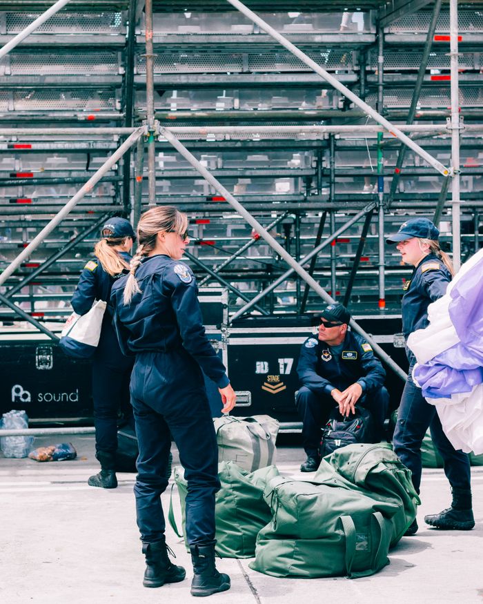 Services Group of uniformed personnel organizing bags in front of a metal scaffold at a public event.
