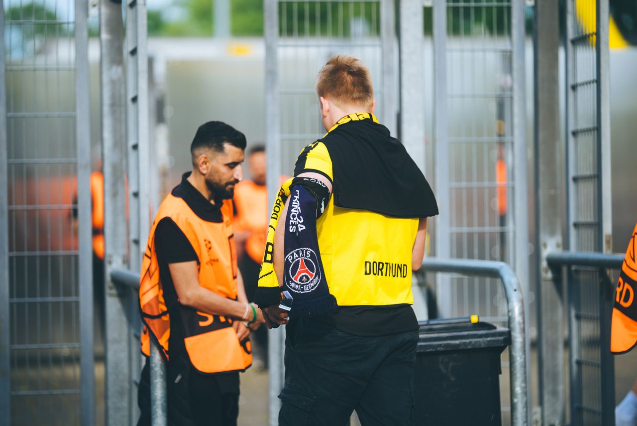 Services Security personnel and a fan at a football stadium checkpoint in Dortmund, Germany.