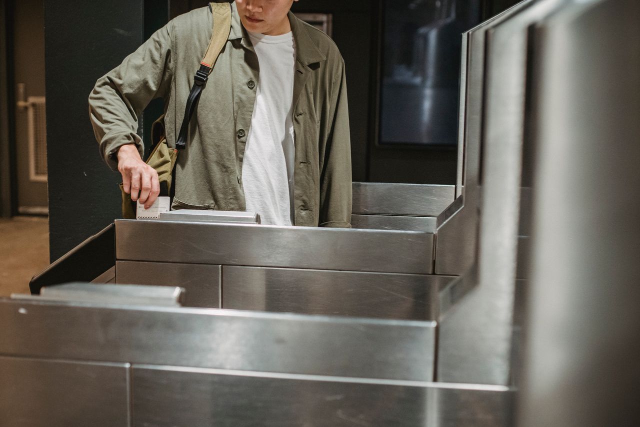Services Crop unrecognizable male passenger in casual clothes with backpack inserting ticket in entrance machine of automated gate while entering modern subway station
